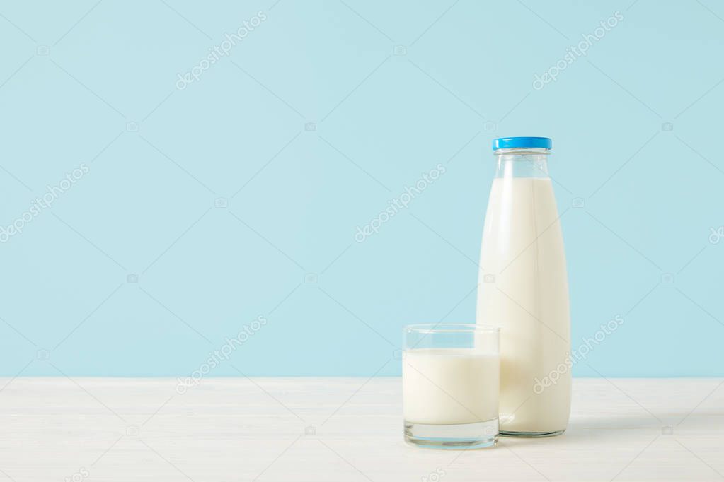 closeup image of milk bottle and milk glass on blue background 
