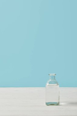 cam şişe su beyaz masa mavi izole