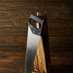 Closeup view of handsaw and log on wooden brown table