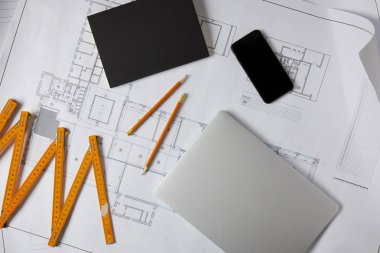 katlanabilir metre, laptop, boş ekran, kalemler, planı üzerine ders kitabı ile smartphone 