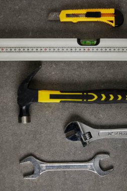 spirit level, hammer, adjustable wrench ans spanner on gray surface clipart