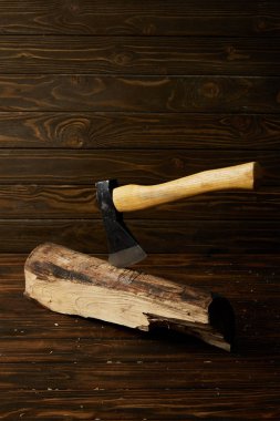 close up shot of sticking axe in log on brown wooden surface clipart