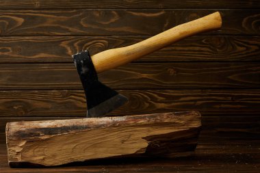 closeup view of sticking axe in log on brown wooden surface  clipart