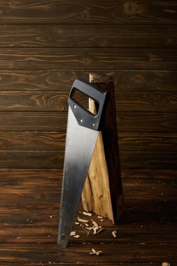 closeup view of handsaw and log on wooden brown table clipart