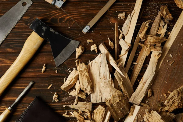 在棕色桌面上的斧头 手锯和木制件 — 图库照片
