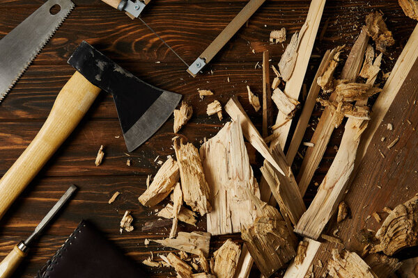 axe, chisel, handsaw and wooden pieces on brown tabletop 
