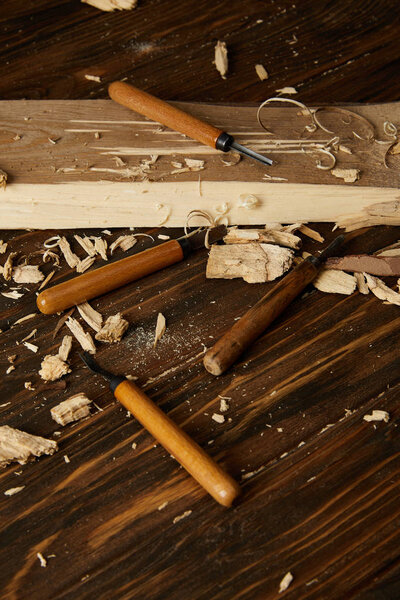 closeup shot of chisels and wooden pieces on brown table