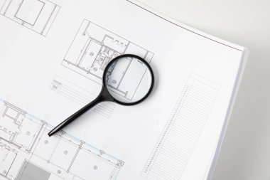 top view of magnifying glass and blueprint on grey, architecture concept  clipart