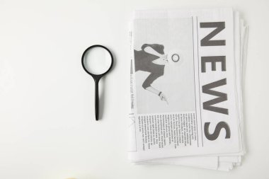 top view of magnifying glass and newspapers isolated on grey clipart