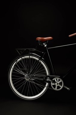 saddle, wheel and pedals of vintage bicycle isolated on black clipart