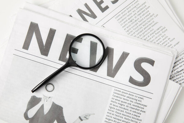 top view of magnifying glass and newspapers, information concept 
