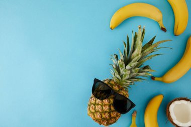 taze Hindistan cevizi, muz ve ananas izole mavi güneş gözlüğü ile üstten görünüm