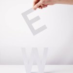 Cropped view of person holding paper letters - e and w, on white background