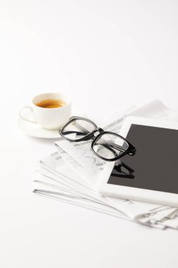 eyeglasses and digital tablet on pile of newspapers and coffee cup, on white clipart