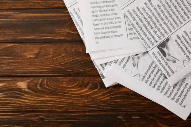 top view of pile of newspapers on wooden background with copy space