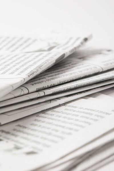 close up of heap of daily newspapers with information, on white