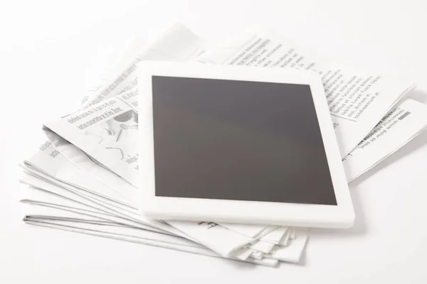 close up of pile of newspapers with digital tablet, on white