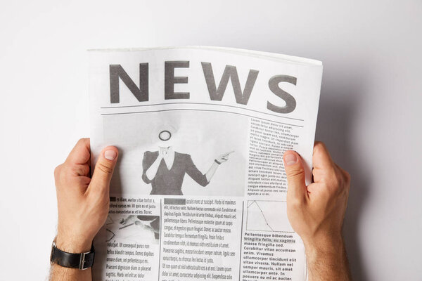 обрезанный взгляд человека, держащего и читающего ежедневную газету
