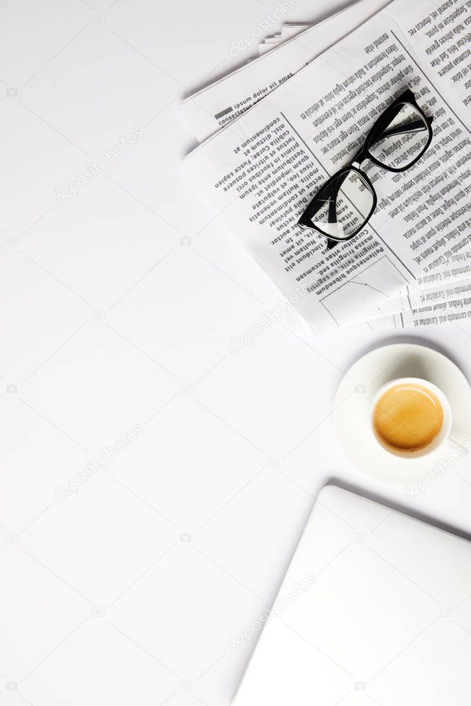 flat lay with eyeglasses, coffee, laptop and newspapers, on white with copy space