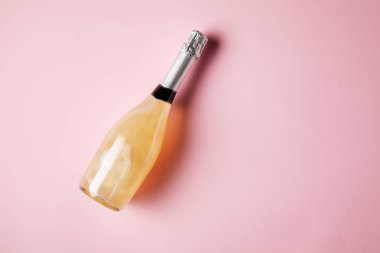 elevated view of bottle of champagne on pink surface clipart