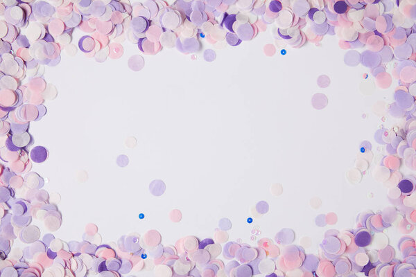 top view of frame of violet confetti pieces on white surface