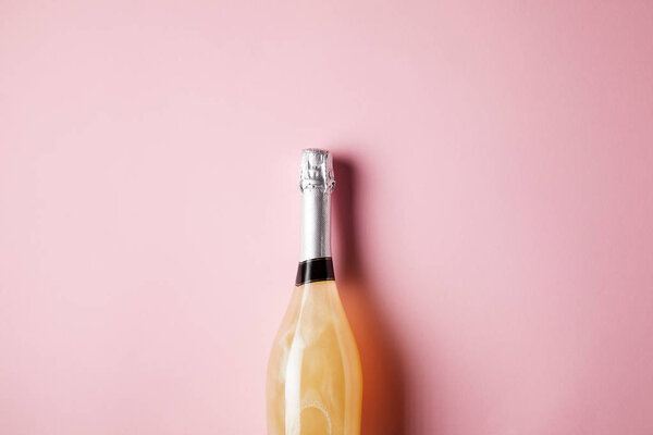top view of bottle of champagne on pink surface