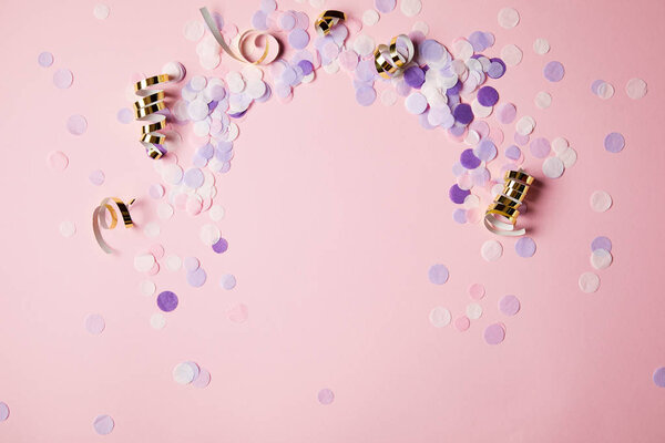 elevated view of violet confetti pieces on pink surface