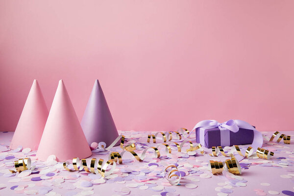 Шляпы для вечеринок, подарочная коробка и конфетти на фиолетовом столе
