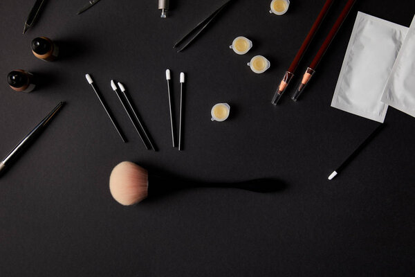 top view of various brushes, pencils and tools for permanent makeup on black