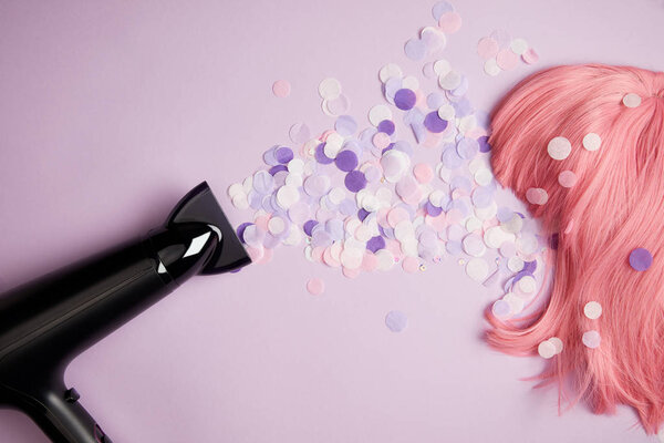top view of hair dryer, confetti and pink wig on purple