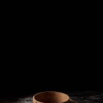 Closeup shot of sieve and rolling pin on wooden table covering by flour isolated on black background