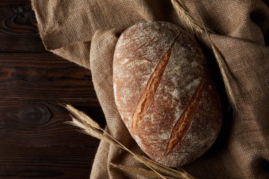 rustik ahşap masa üzerinde ekmek, buğday ve çul üstten görünüm 
