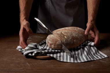 Erkek baker ekmek, bıçak ve çul tabloyla yakınındaki ayakta kırpılmış atış 