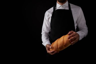 siyah arka plan üzerine izole ekmek tutan önlük erkek baker kırpılmış atış 