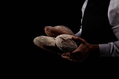 siyah arka plan üzerine izole ekmek türleri tutan önlük erkek baker kırpılmış görüntü 