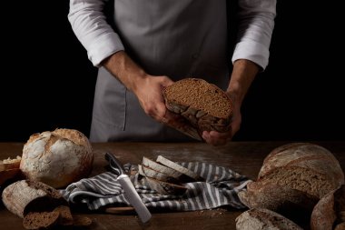 Erkek baker ekmek bıçağı, ekmek ve çul ile masa üzerinde tutarak önlük kadeh kırpılmış 
