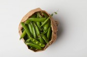top view of pea pods in paper bag on white surface