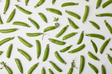 top view of ripe pea pods spilled on white surface clipart