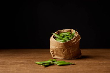 paper bag of pea pods on wooden tabletop clipart