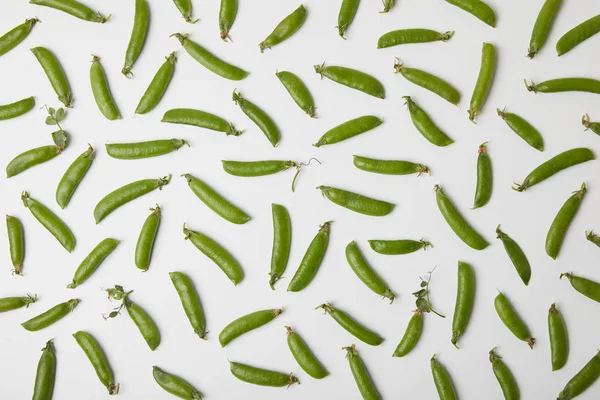 在白色表面洒下的绿色豌豆荚的顶部视图 — 图库照片