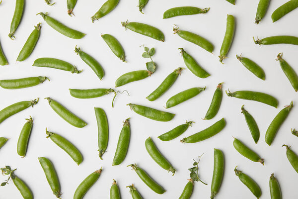 top view of ripe pea pods spilled on white surface