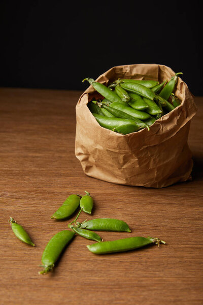 paper bag of ripe pea pods on wooden tabletop