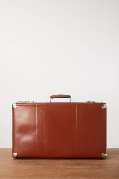Closed leather suitcase on wooden background