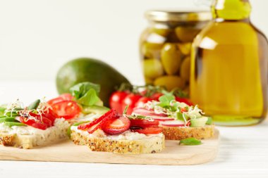 yakın çekim, lezzetli çeşitli sandviç kesme tahtası üzerinde avokado ve zeytin yağı ile vurdu