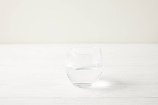 close-up shot of single glass of water on white wooden tabletop