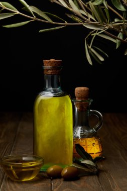 bottles of various olive oil on wooden surface clipart