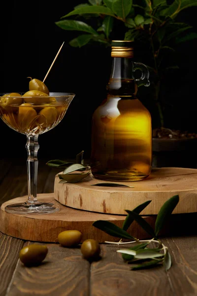 olive oil in bottle with olives in vintage glass on stacked boards