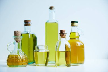 different bottles of aromatic olive oil and jar on white background clipart