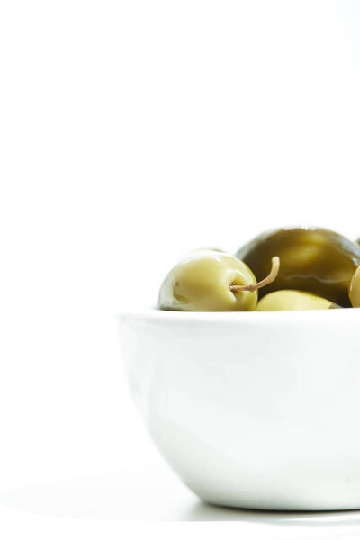 close up view of bowl with  green olives isolated on white background
