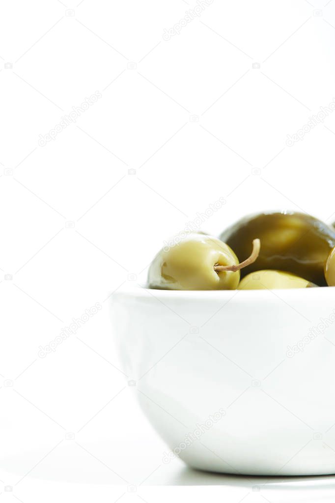close up view of bowl with  green olives isolated on white background